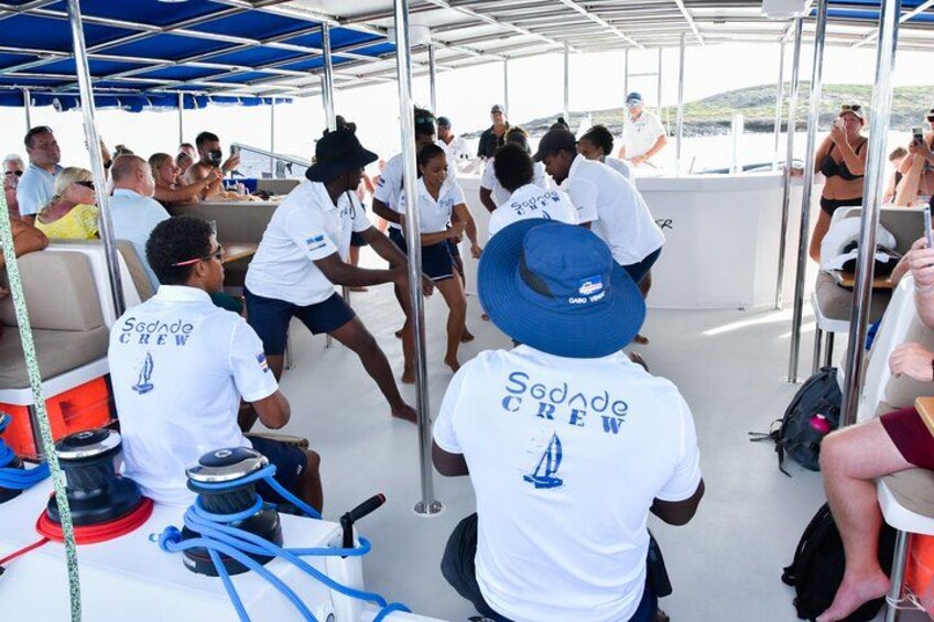 People on a boat wearing 'Sodade Crew' shirts, some standing and others seated. 5