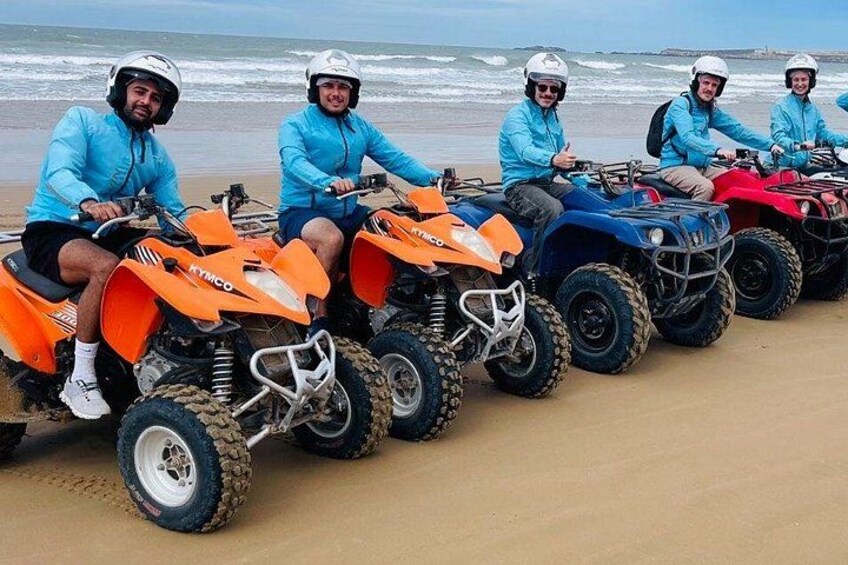 Cuatro cuatrimotos alineadas en una playa arenosa, con el océano al fondo. 2
