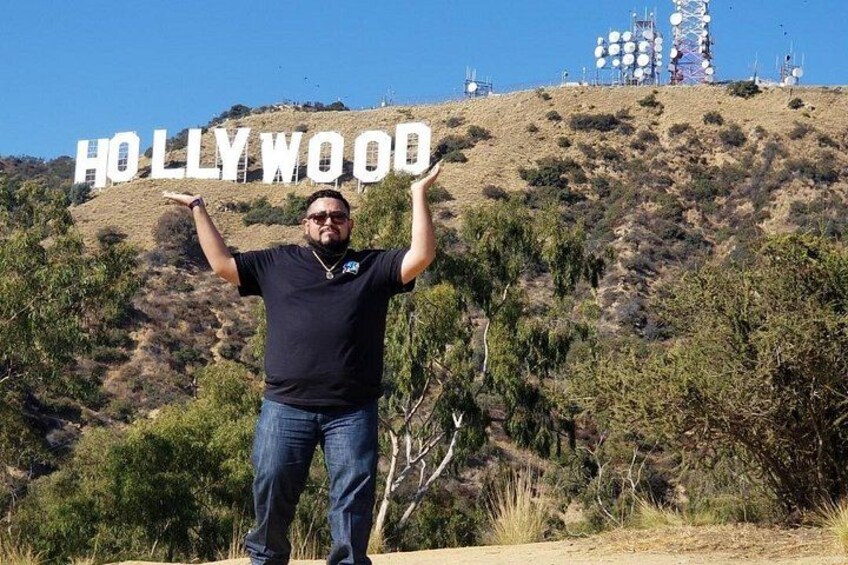 Een persoon staat met armen omhoog voor het Hollywood-bord. 5