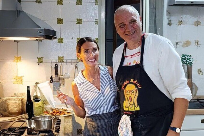 Twee personen in een keuken met een fornuis, een pan en een fles. 2