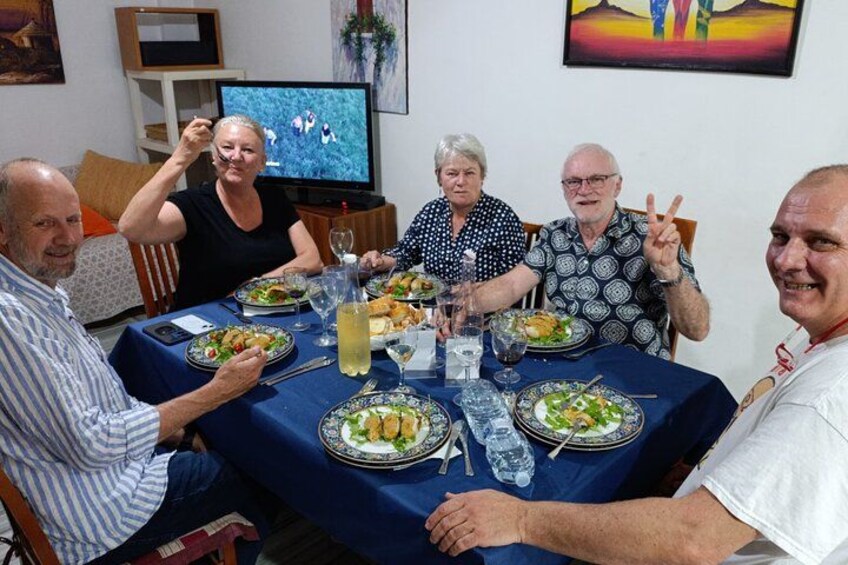 Un gruppo di persone sedute attorno a un tavolo con cibo e bevande. 4