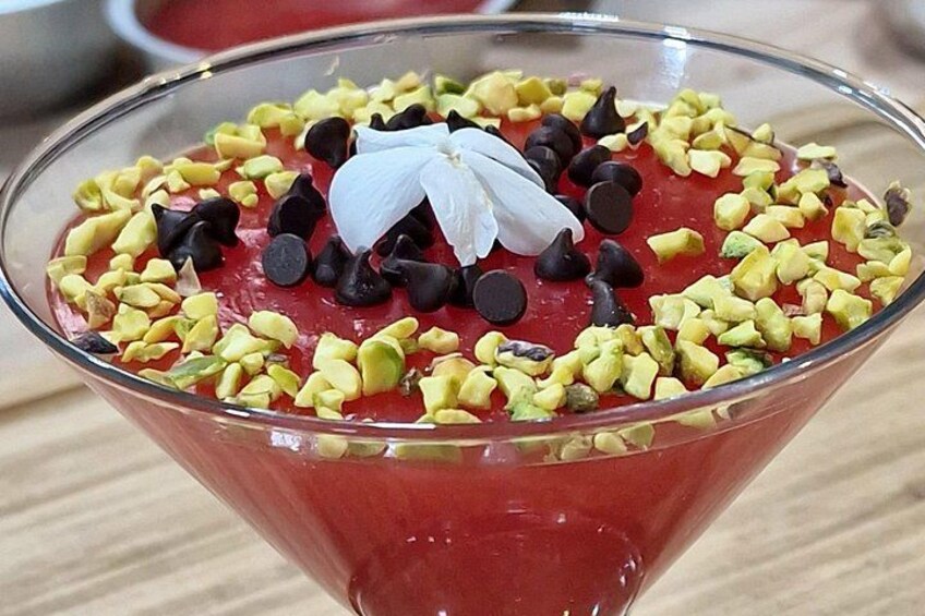 Postre en un bol de vidrio con gelatina roja, chips de chocolate y pistachos picados. 5