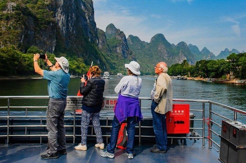 En grupp människor på en båt som fotograferar ett bergigt landskap. 5