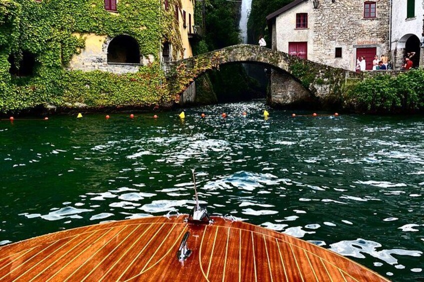 A wooden boat on a river with a stone bridge and buildings in the background. 3