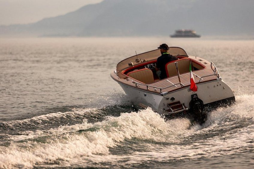 A motorboat with a person steering, moving through choppy water with waves, and a distant ship in the background. 3