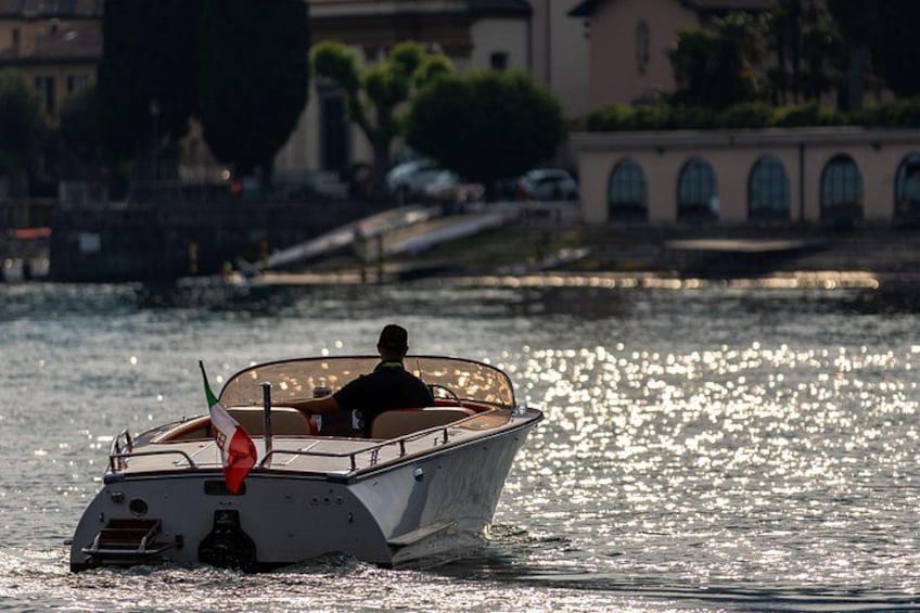 A boat on water with a person on board, a red flag, and buildings in the background. 5