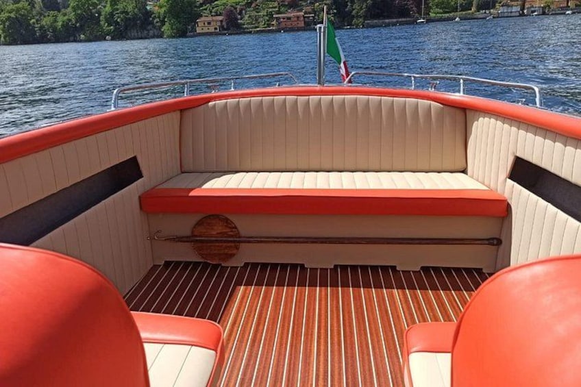 A boat's interior with a striped floor, cushioned seating, and a flag. 2