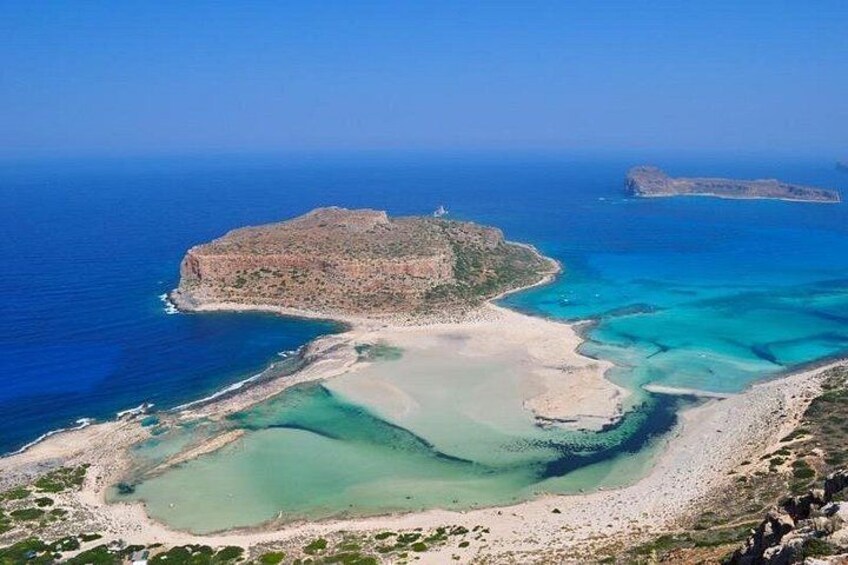 Un paisaje costero con una isla rocosa destacada, aguas azules cristalinas y una playa arenosa. 1