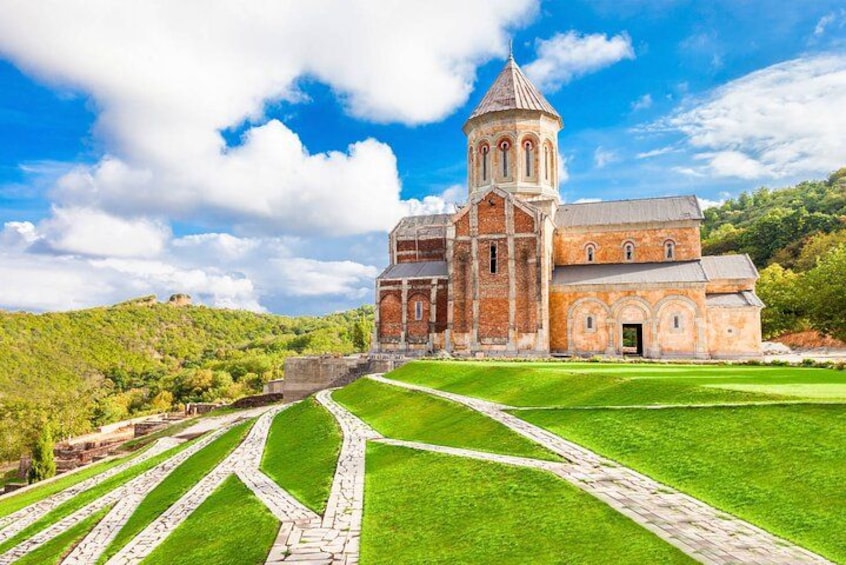Una chiesa storica con un campanile, immersa in un prato curato e percorsi in pietra. 2
