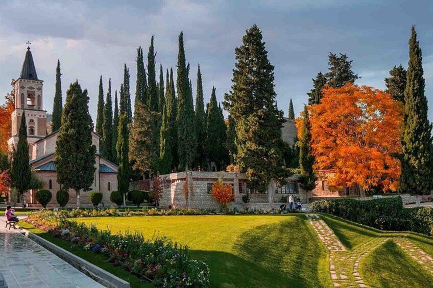 A church with a bell tower, a well-maintained lawn, tall cypress trees, and autumn-colored foliage. 3