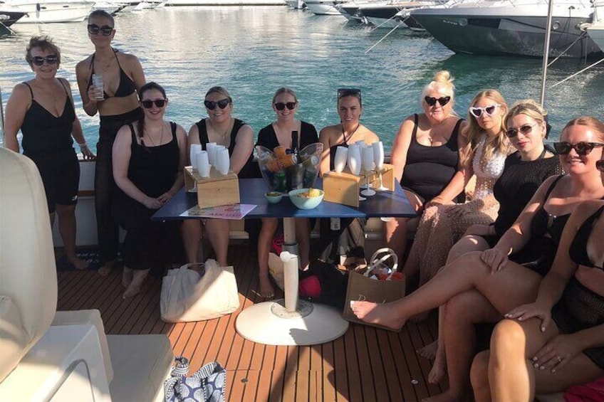 A group of people on a boat with a table set for drinks and snacks. 5