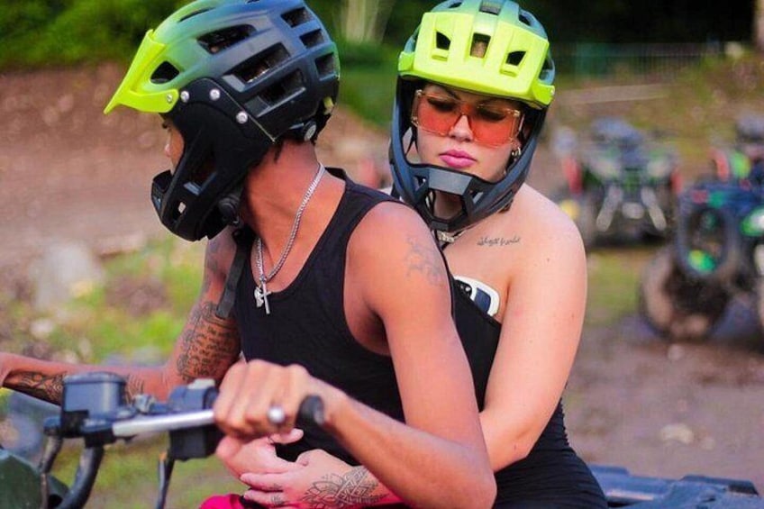 Zwei Personen auf einem Motorrad, mit Helmen und schwarzen Tanktops. 1