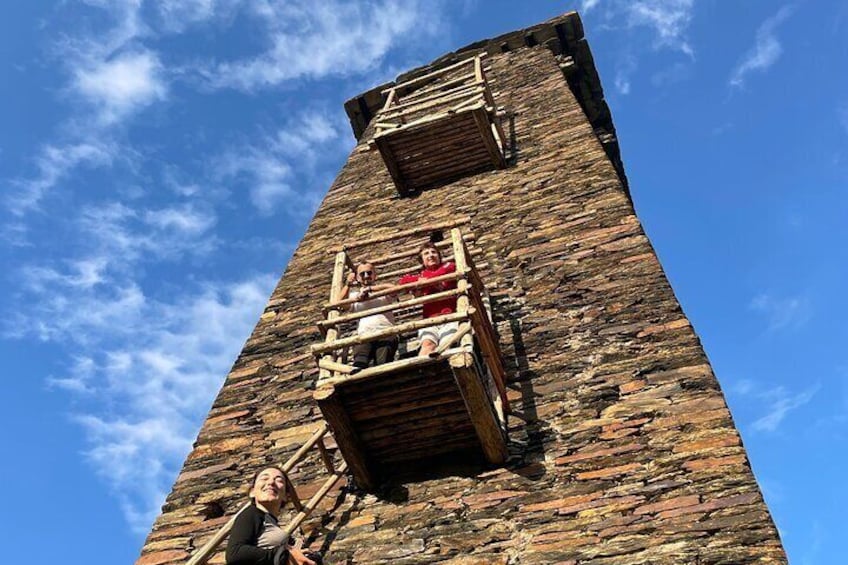 A stone tower with wooden balconies and a person standing at its base. 5
