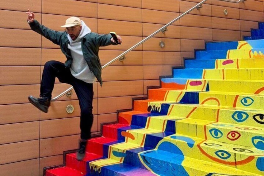 A person jumping off a colorful staircase with geometric patterns. 5