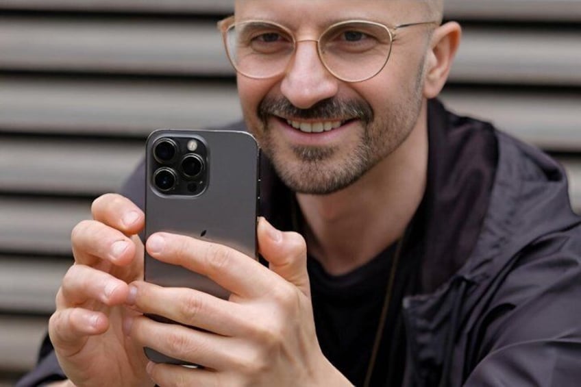 A person holding a smartphone with a triple camera setup. 1