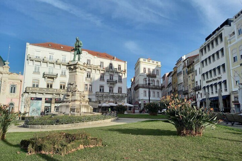 A square with a statue, surrounded by historic buildings and a well-maintained lawn. 1
