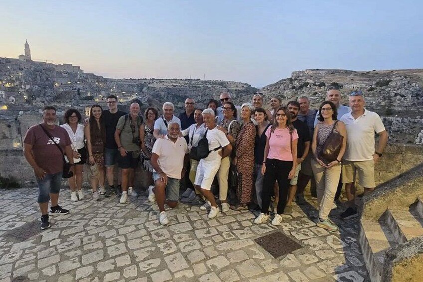 A group of people standing on a stone-paved area overlooking a cityscape with historical buildings. 3