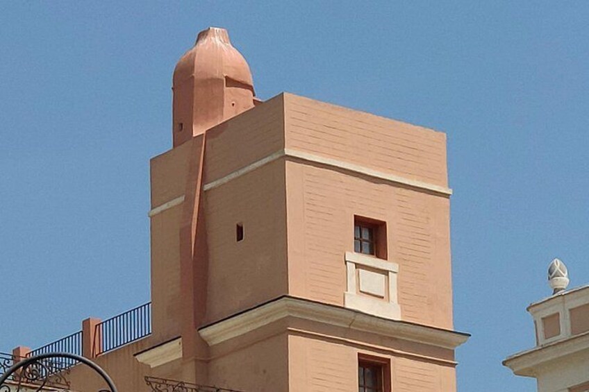 Un edificio con fachada rosada, una ventana pequeña y una estructura en forma de cúpula en la parte superior. 3