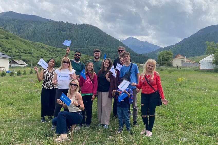 A group of people in a grassy field with mountains in the background. 3