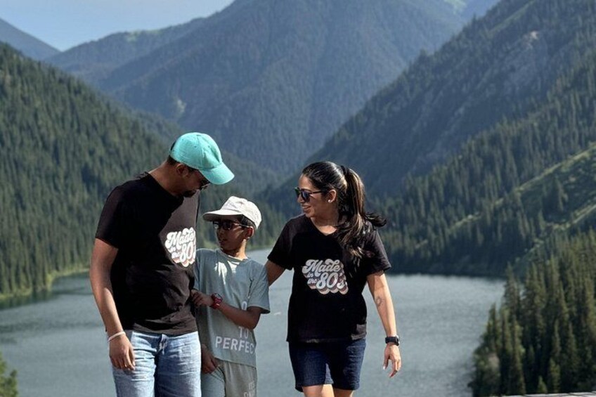 A group of people standing by a lake with mountains in the background. 5