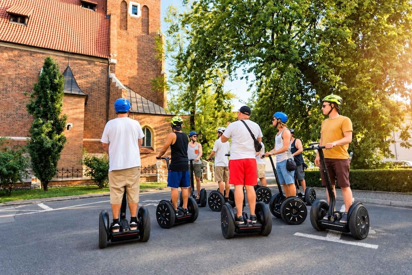 Ryhmä ihmisiä ajaa segway-lautoilla kadulla, taustalla näkyy kirkko ja puita. 4