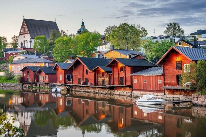A waterfront with red wooden buildings, a boat docked, and a church with a dome. 3