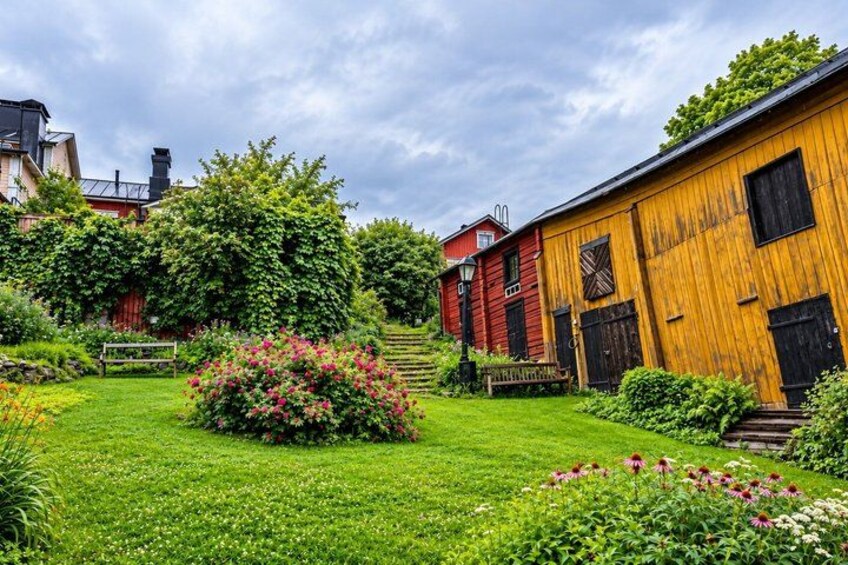 Ett lantligt landskap med en träladugård, ett rött hus och en välskött trädgård. 4