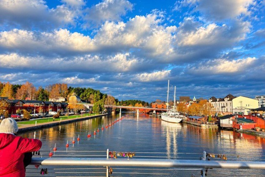 En flod med båtar, en segelbåt och byggnader längs stränderna. 3