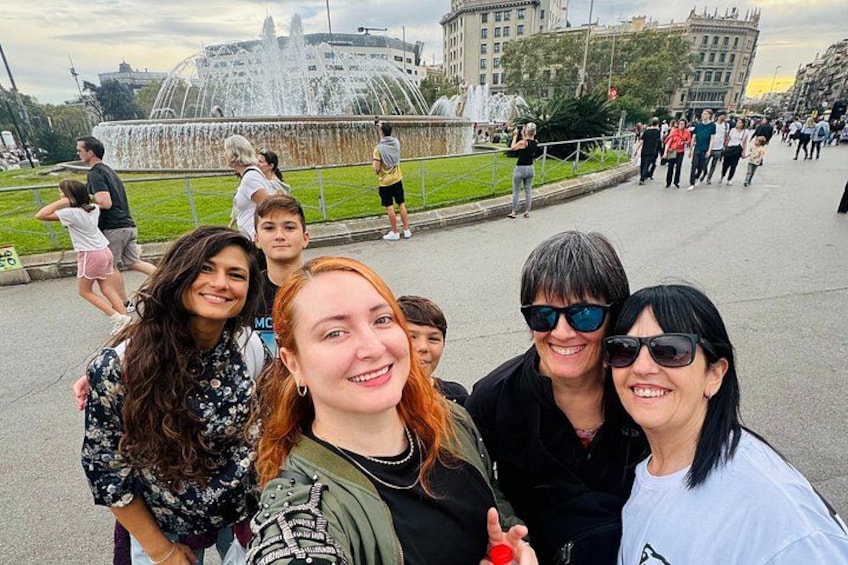 En gruppe mennesker tager en selfie foran en springvand med en kuppelstruktur i baggrunden. 4