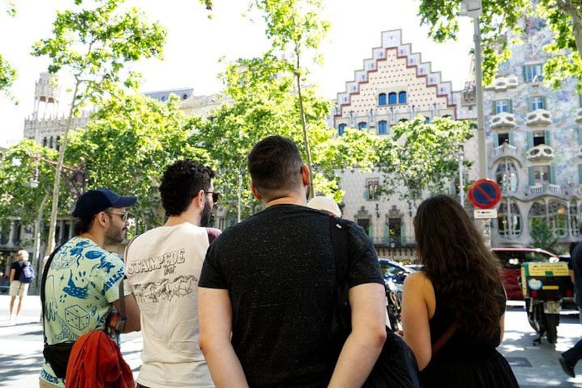 A group of people standing on a street with trees and buildings in the background. 2