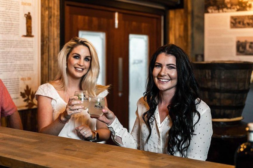 Two people holding glasses with a label 'MICHEL' at a bar with wooden elements and a door in the background. 3