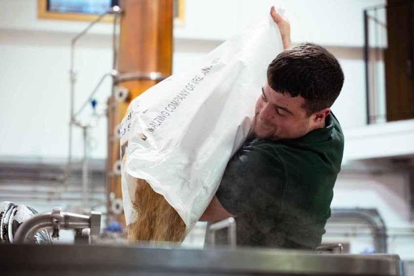 A person in a green shirt lifting a white bag with text. 4