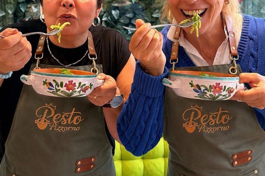 To personer i forklæder med logoet 'Pesto Pizzeria' holder skåle med mad. 4