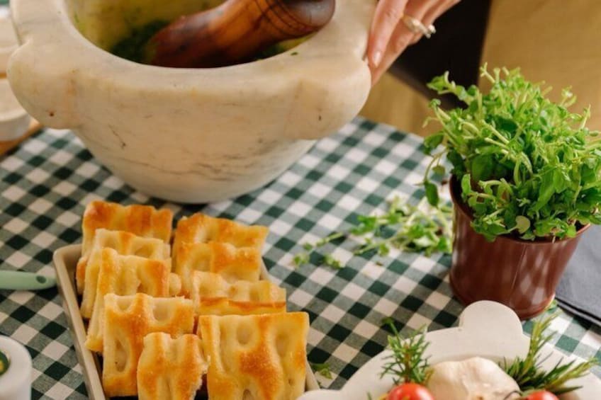 Een geruit tafelkleed, een kom soep, een pan groenten, een kleine plant en een bord gevulde noedels. 4