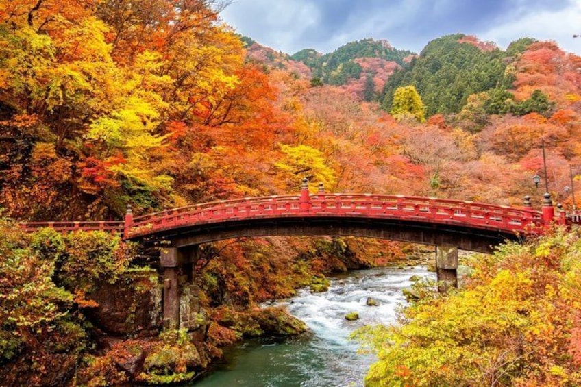 A red bridge over a river in a forested area with autumn foliage. 3