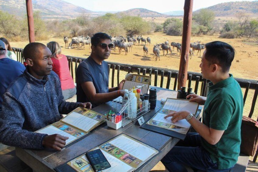 Un groupe de personnes est assis à une table, et on peut voir, en arrière-plan, un troupeau d’animaux. 5