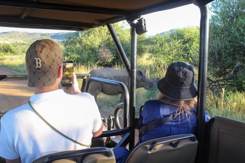 Deux personnes à bord d’un véhicule de safari, dont l’une prend une photo. 1