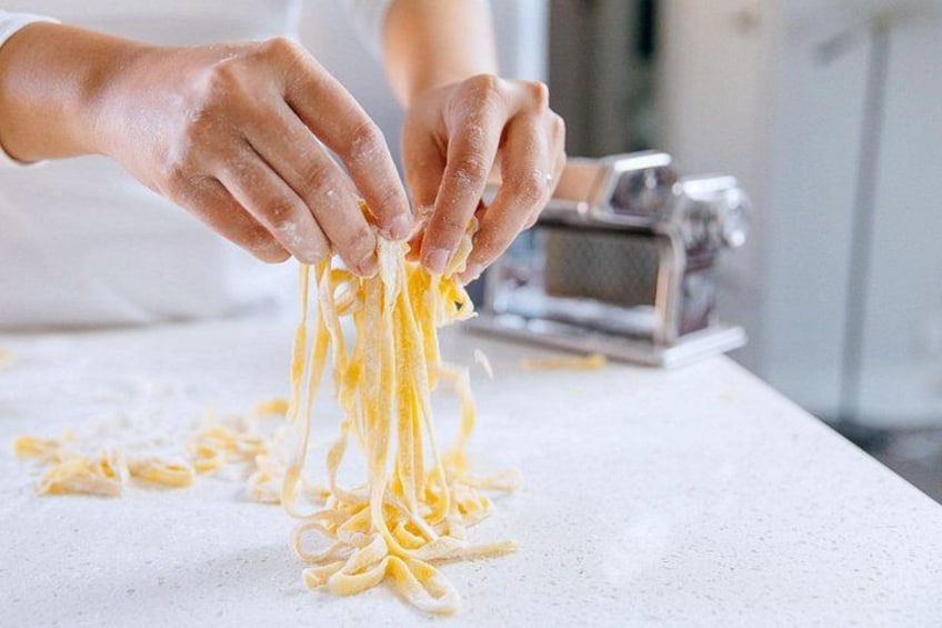 Hands peeling pasta from a machine. 2