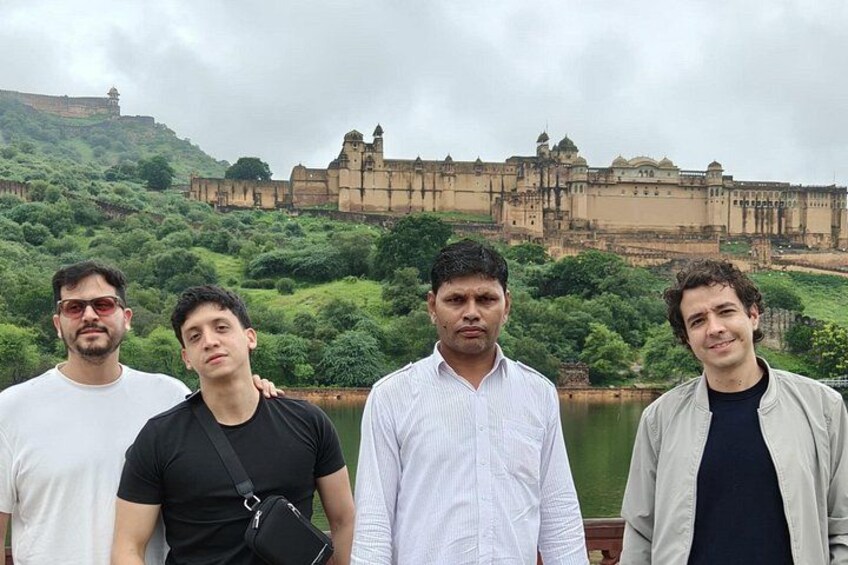 Four people standing in front of a historic fort with lush greenery and a river in the background. 5