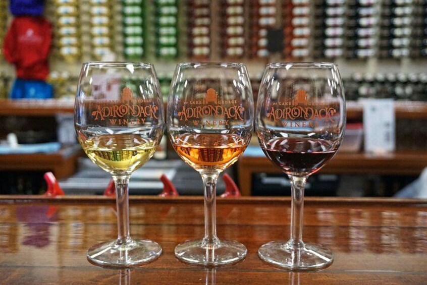 Three wine glasses with different colored liquids on a bar counter. 1