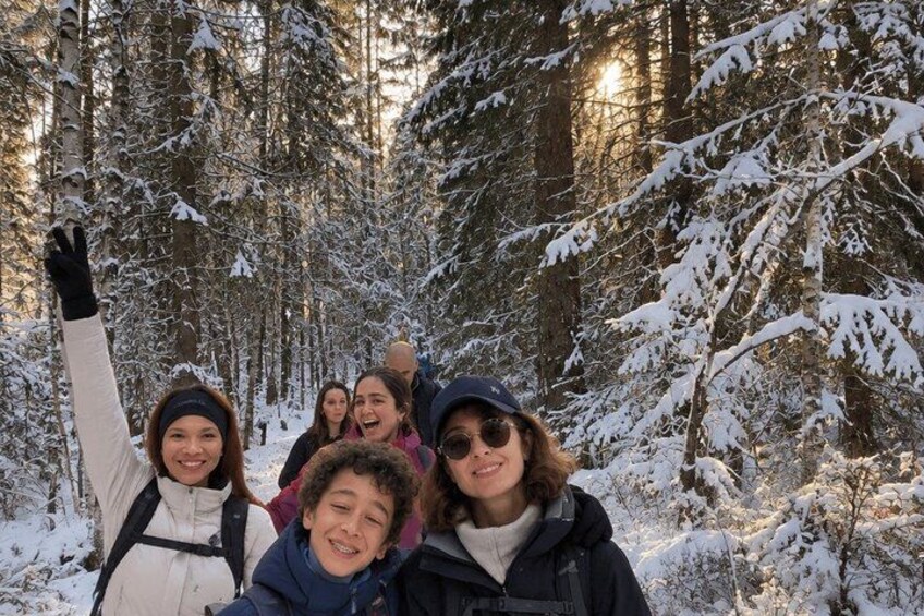 A group of people in a snowy forest with tall trees and sunlight filtering through. 4