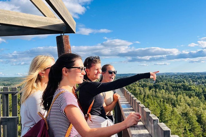 A group of people standing on a wooden observation deck overlooking a forested landscape. 1