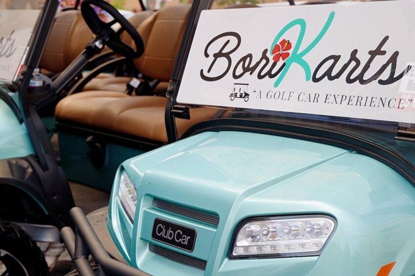 A golf cart with a Club Car logo and a sign that reads 'Bori Karts - A Golf Car Experience'. 4