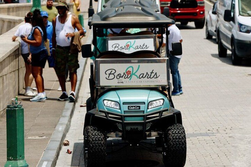 A golf cart with a sign reading "Boro Karts" on a city street. 1