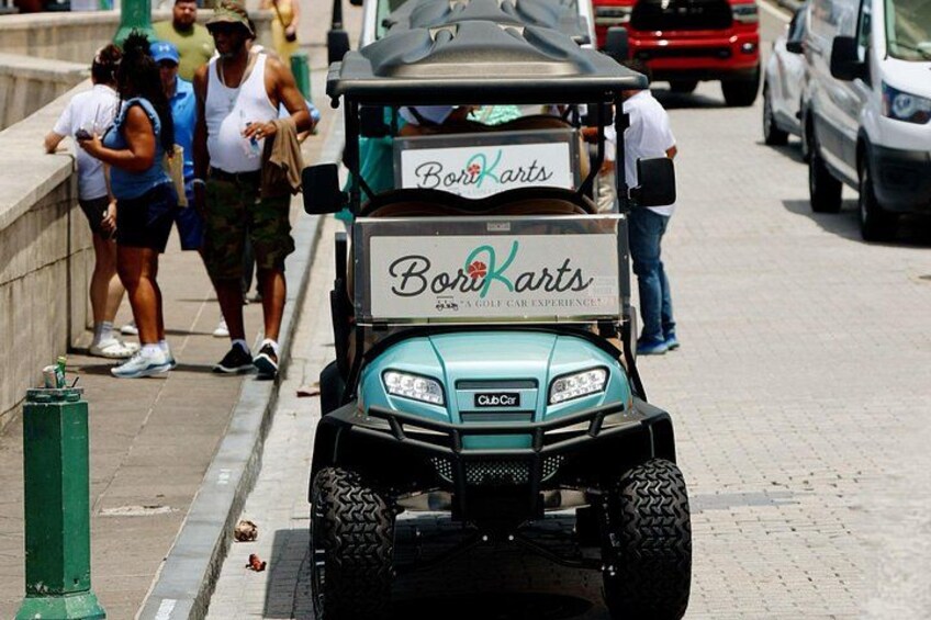 A golf cart with a 'Boro Karts' sign parked on a sidewalk. 1