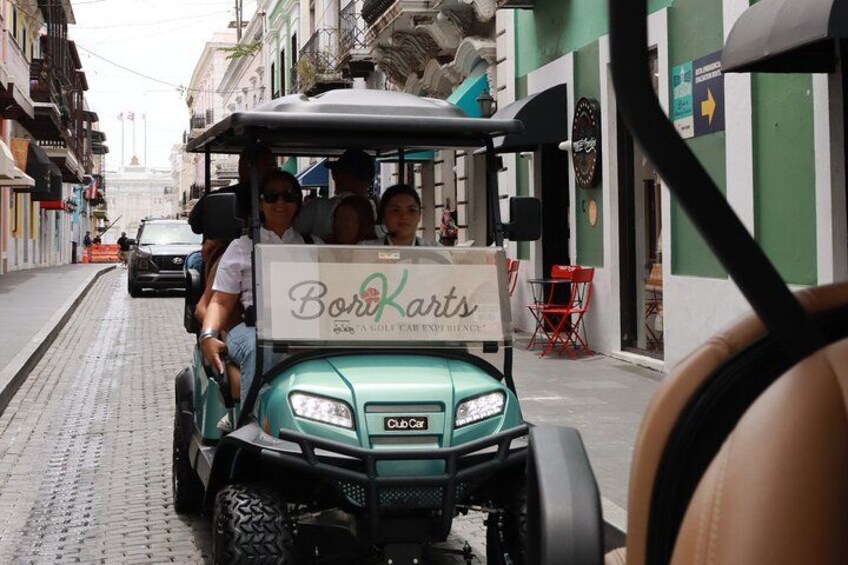 A golf cart with a sign reading 'Boriarts' parked on a cobblestone street. 5