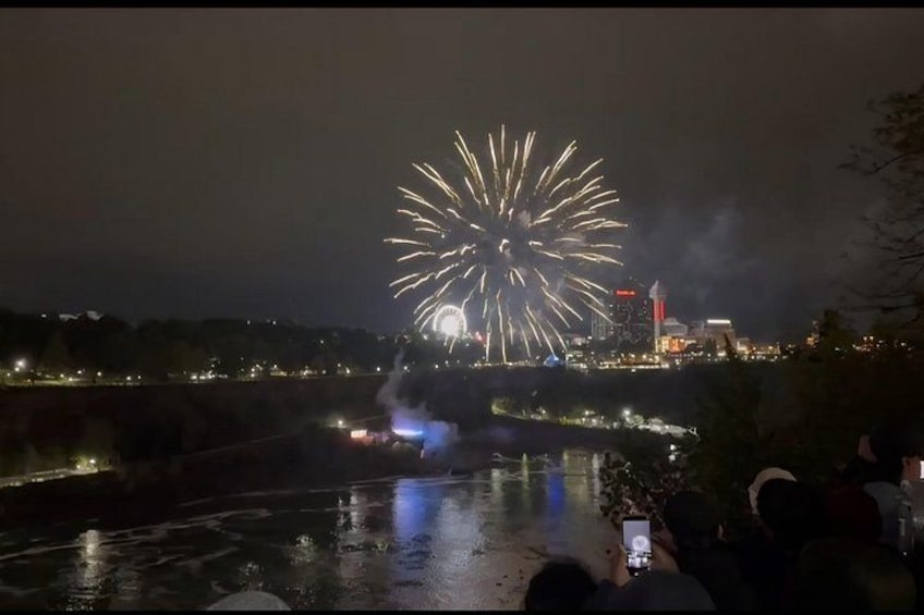 Feuerwerk über einem Fluss mit einer Brücke und Stadtlichtern im Hintergrund. 1