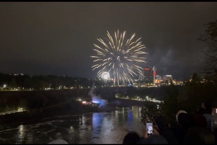Feuerwerk über einem Fluss mit einer Brücke und Stadtlichtern im Hintergrund. 1