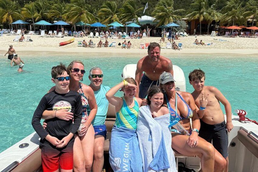 A group of people on a boat in a tropical beach setting with palm trees and umbrellas. 2