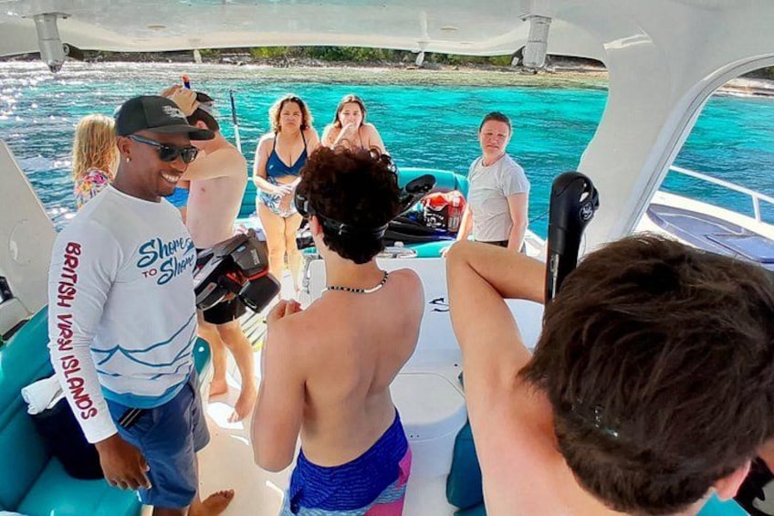 A boat with people on board, a person holding a camera, and a clear blue sea in the background. 2